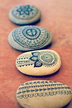 three painted rocks sitting on top of a wooden table next to each other with designs on them