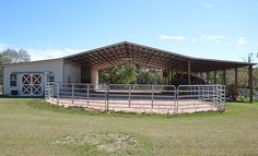 a large open area with a metal fence and horse stalls on the side of it