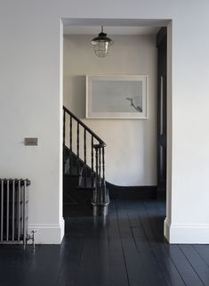 an empty hallway with black and white walls, wood floors and a painting on the wall