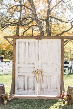 an outdoor ceremony with two white doors and flowers on the grass, surrounded by barrels