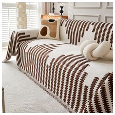 a living room with a white couch covered in brown and white striped blankets on it