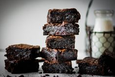 a stack of brownies sitting on top of a table next to a glass of milk