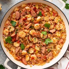 a large pan filled with shrimp and rice on top of a table next to bread