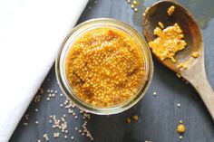 a spoon with some food in it next to a jar filled with yellow stuff on top of a table