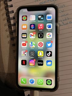 an iphone sitting on top of a table next to a notepad with writing on it