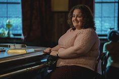 a woman sitting at a table smiling for the camera