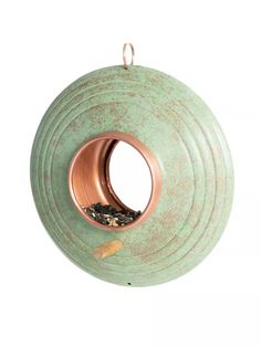 a green bird feeder hanging on a white wall