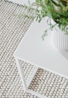 a white table sitting on top of a rug next to a potted green plant