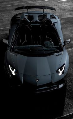 a black and white photo of a sports car with its hood up in the dark