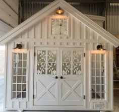 a white house with two doors and windows on the front door is lit up by lights