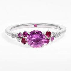 a pink sapphire and diamond ring with three stones on the band, set in white gold