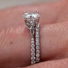 a close up of a person's hand with a diamond ring on their finger