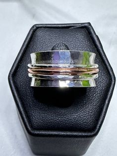 three different colored rings sitting on top of a black ring box with white and gold bands