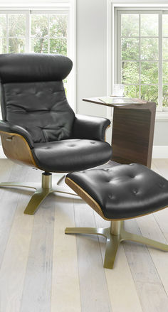 a black leather recliner chair and ottoman in front of a window with white walls