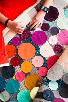 a woman sitting on top of a bed covered in lots of different colored circles