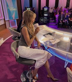 a woman sitting at a table with a cup in her hand