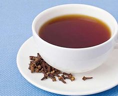 a cup of tea and some cinnamon sticks on a white saucer with blue background