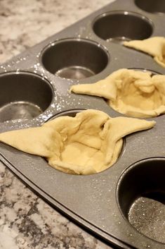 three uncooked dumplings in a muffin tin