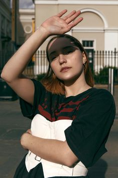 a woman with her hands up in the air while wearing a black and white shirt