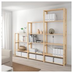 a living room filled with furniture and bookshelves on top of wooden shelves in front of a white wall