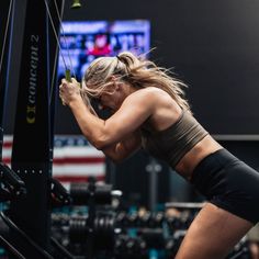 a woman doing squats on a machine in a gym with an american flag behind her