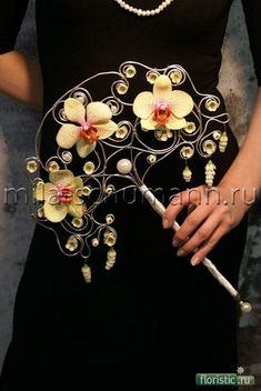 a woman wearing a black dress holding a white stick with flowers on it