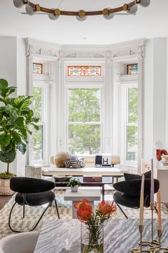 a living room filled with lots of furniture next to a large window and potted plant