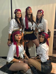 four women dressed up in pirate costumes posing for a photo together, with one woman sitting on the floor