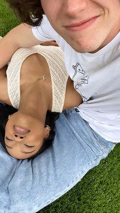 a young man laying on the ground with his arm around a woman's head