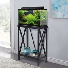 a fish tank sitting on top of a stand in front of a window next to a vase