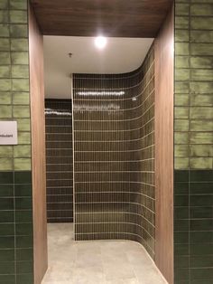 an empty bathroom with green tile walls and wood trimmings on the shower wall