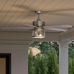 a ceiling fan with a light on top of it in front of a porch area