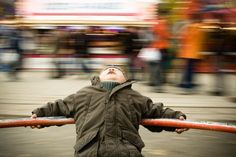 a little boy standing in the street with his arms out and looking up at something