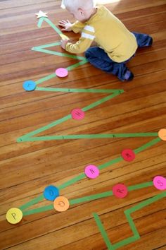 a toddler sitting on the floor playing with a paper tree