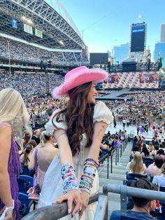 a woman wearing a pink hat and bracelets at a sporting event in a stadium