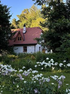 a white house surrounded by trees and flowers