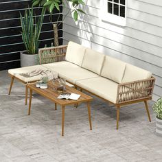 a couch and coffee table on a patio with potted plants in the background,