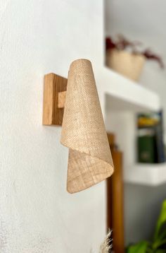 a wooden light fixture mounted to the side of a white wall next to a potted plant