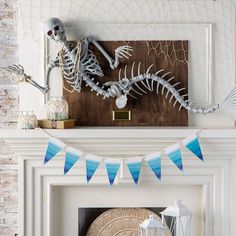 a fireplace mantel decorated with skeletons and blue pennants for the skeleton birthday party