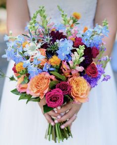 a bride holding a bouquet of colorful flowers