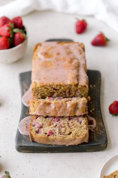 two slices of cake sitting on top of a cutting board next to some strawberries