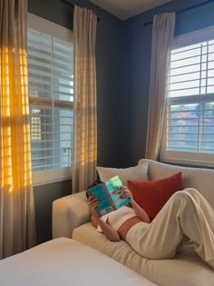 a person laying on a couch reading a book