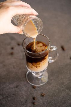 someone pours coffee into a glass mug