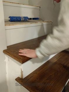 a person reaching down on some shelves with their hand in the bottom shelf and another hand holding onto the top shelf