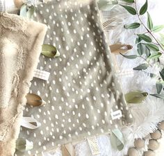 a blanket with white polka dots on it next to a pile of feathers and leaves