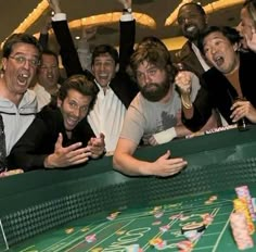 a group of men standing next to each other in front of a roule table