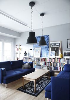 a living room with blue couches and bookshelves