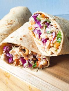 a burrito cut in half sitting on top of a wooden cutting board