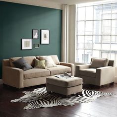 a living room with green walls and zebra print rugs on the hardwood flooring