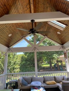 an outdoor living area with couches, tables and ceiling fans